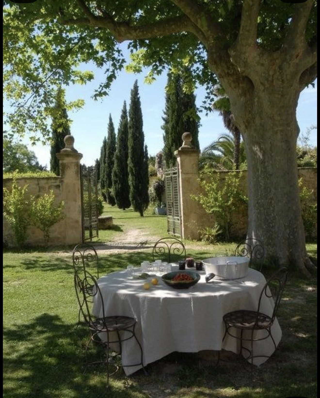 A linen covered table beneath a tree in a sunlit garden